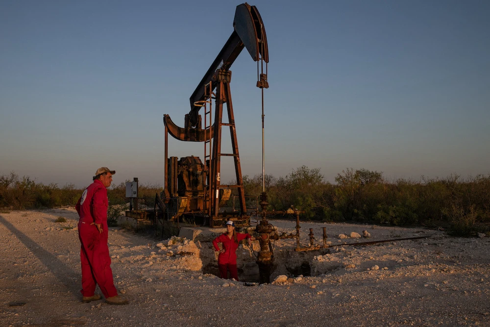 An oil well control specialist and oil and gas lawyer survey an excavated pumpjack with a leaking surface casing in Ward County, Texas, US, Aug. 6, 2024. Reuters