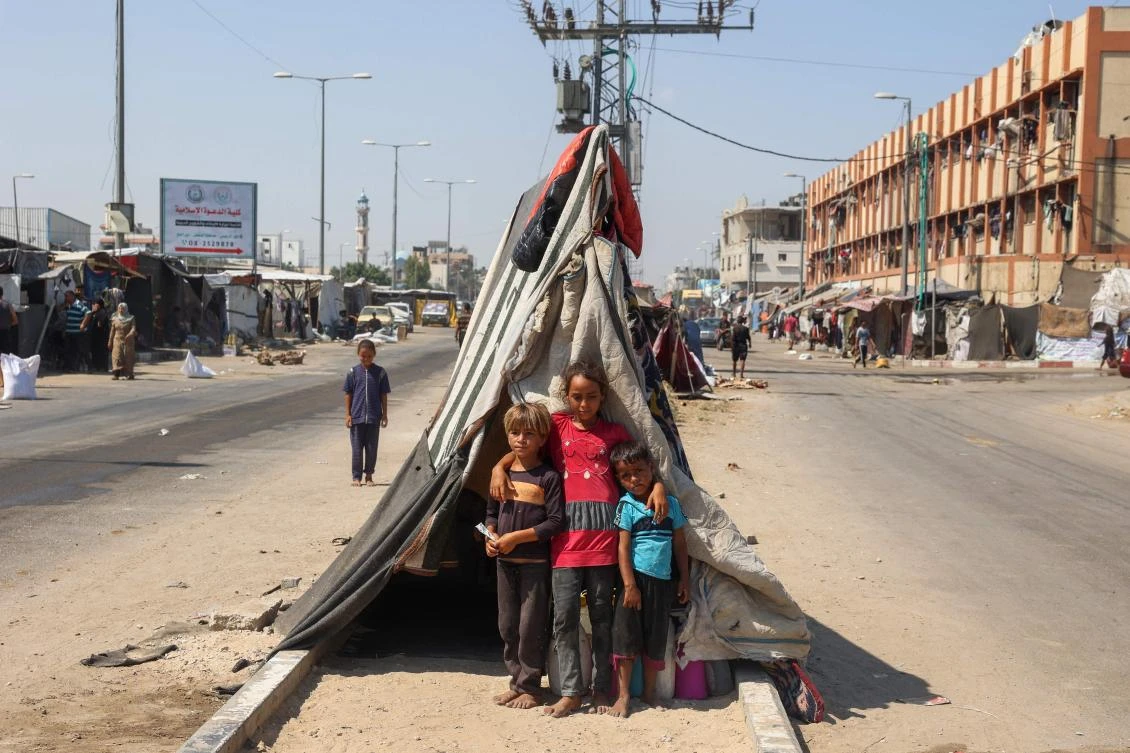 Palestinian children pose for a picture near their tent set on a road's median at a makeshift displacement camp set up along a road in Deir el-Balah in the central Gaza Strip amid the ongoing conflict between Israel and the Palestinian Hamas movement. (File/AFP)