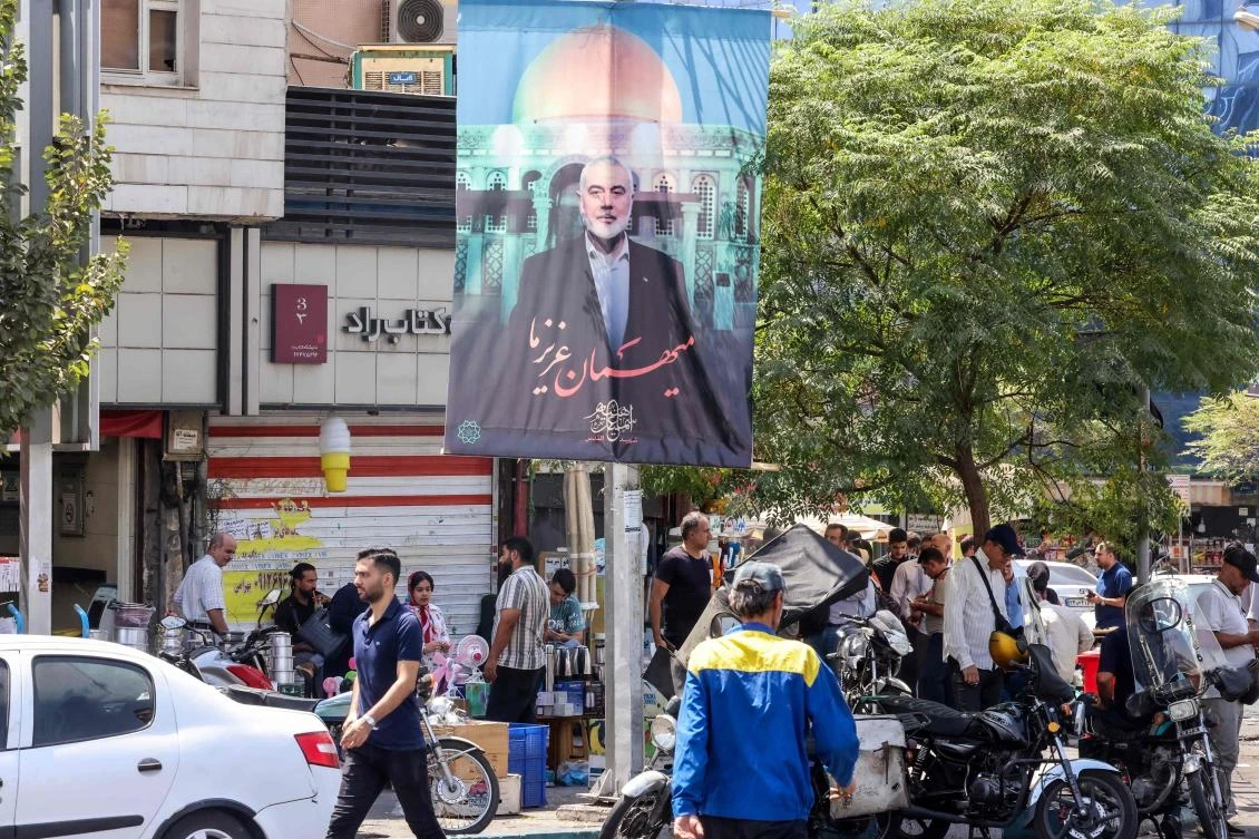 People walk past a banner featuring a picture of the late Hamas political leader Ismail Haniyeh, who was killed in an attack while in Iran, in Tehran on August 20, 2024. (AFP)