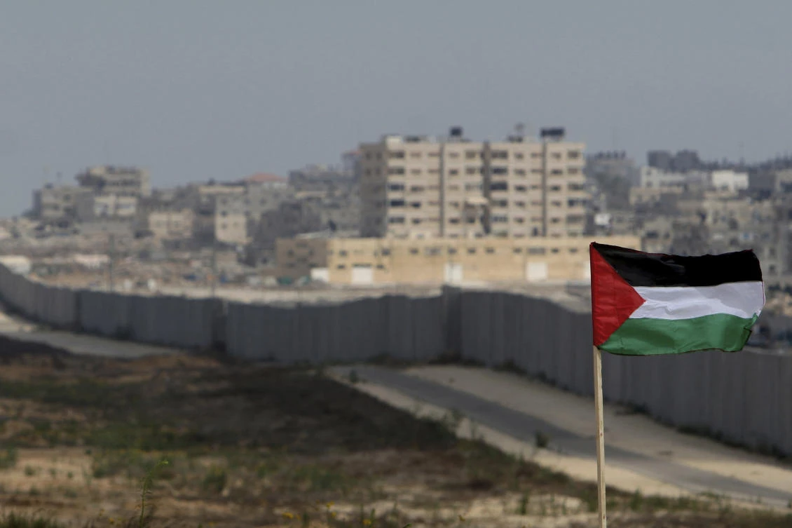 A Palestinian flag is seen with the background of a section of the wall in the Philadelphi corridor between Egypt and Gaza, on the background, near the southern Gaza Strip town of Rafah. (File/AP)