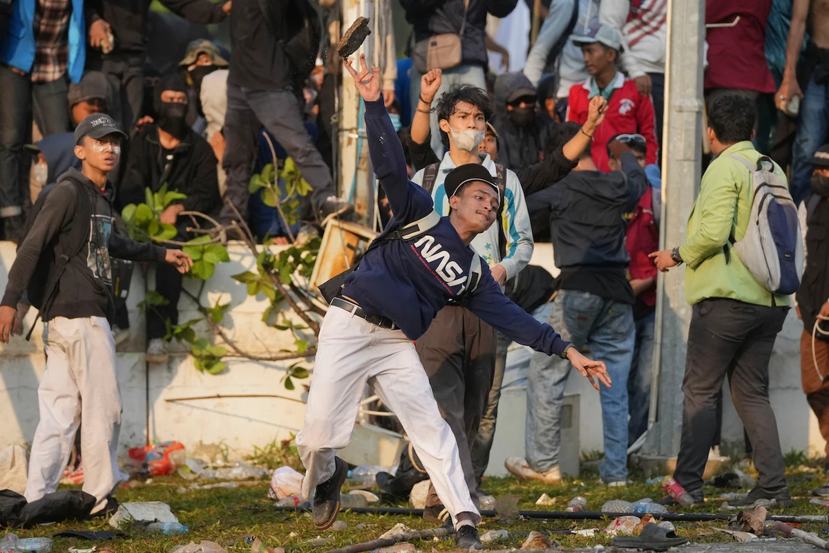 A protester throws a rock toward riot police during a rally against controversial changes to election laws, at the parliament building in Jakarta, Indonesia, Thursday, Aug. 22, 2024. (AP)