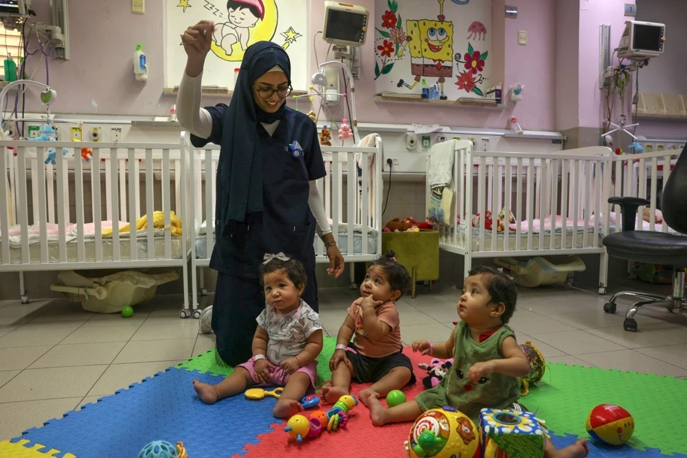 A nurse entertains triplets Najoua, Nour, and Najmeh. (AFP)
