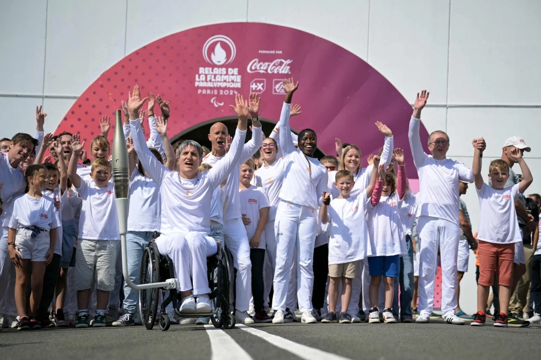 Former French wheelchair fencer Emmanuelle Assmann (C-L) with the torch of the Paris 2024 Paralympic Games on her wheelchair and other torchbearers during the arrival of the Paralympics flame at the entrance of the Channel Tunnel in Coquelles, northern France on Aug. 25, 2024. (AFP)