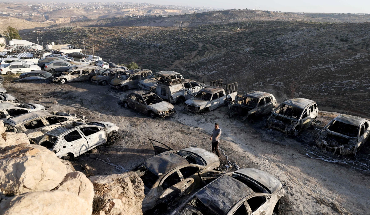 A Palestinian man walks past burnt out vehicles stationed in car park following a reported Israeli settlers attack in the town of Burqah, east of the West Bank city of Ramallah on June 7, 2024. (AFP)