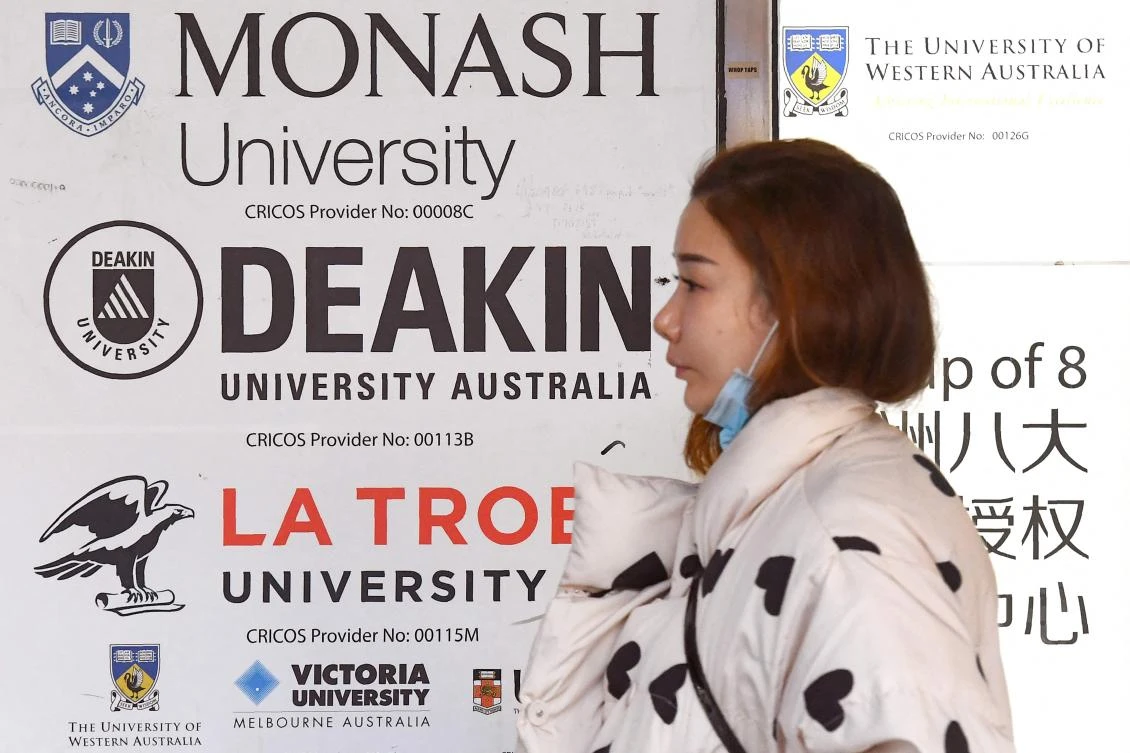 A woman walks past signage advertising Australian universities in Melbourne's central business district on June 10, 2020. (AFP)
