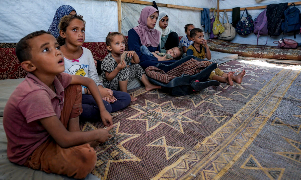 Displaced infant Abdel-Rahman Abuel-Jedian, 11-month-old, who suffers from polio, is carried by his mother, center, at a makeshift tent camp in Deir al-Balah, central Gaza Strip, Tuesday, Aug. 27, 2024. (AP)