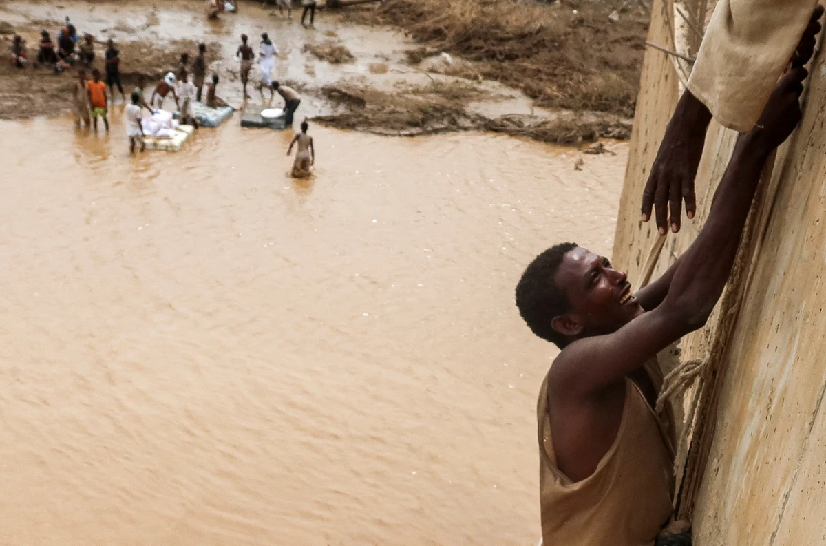 A survivor is being helped to climb a wall, following devastating floods, in South Tokar, Red Sea State, Sudan, August 28, 2024. (Reuters)