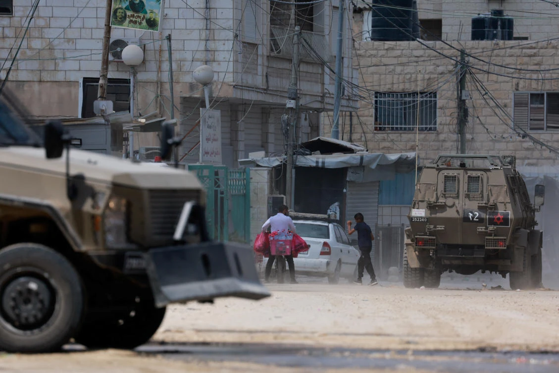 A Palestinian walks next to armored vehicles during an Israeli raid in Jenin, in the Israeli-occupied West Bank, August 31, 2024. (REUTERS)