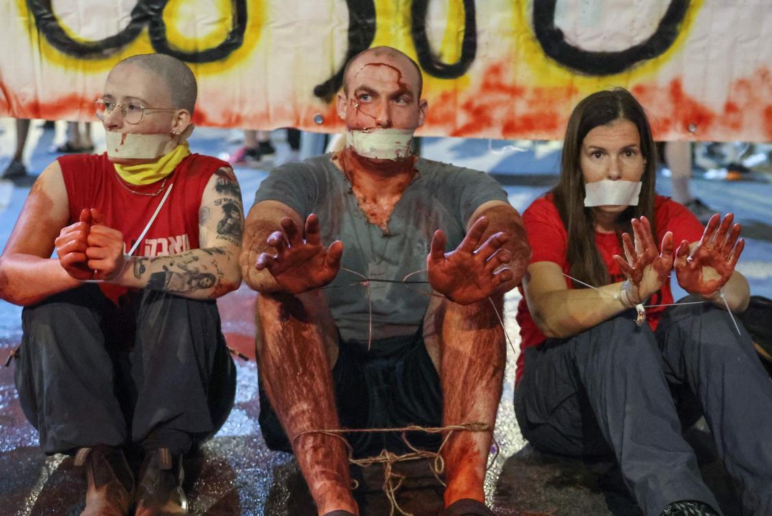 Demonstrators covered in fake blood stage a sit-in during a protest calling for the release of Israelis held hostage by Palestinian militants in Gaza since October, in Tel Aviv amid the ongoing conflict in the Gaza Strip. (File/AFP)