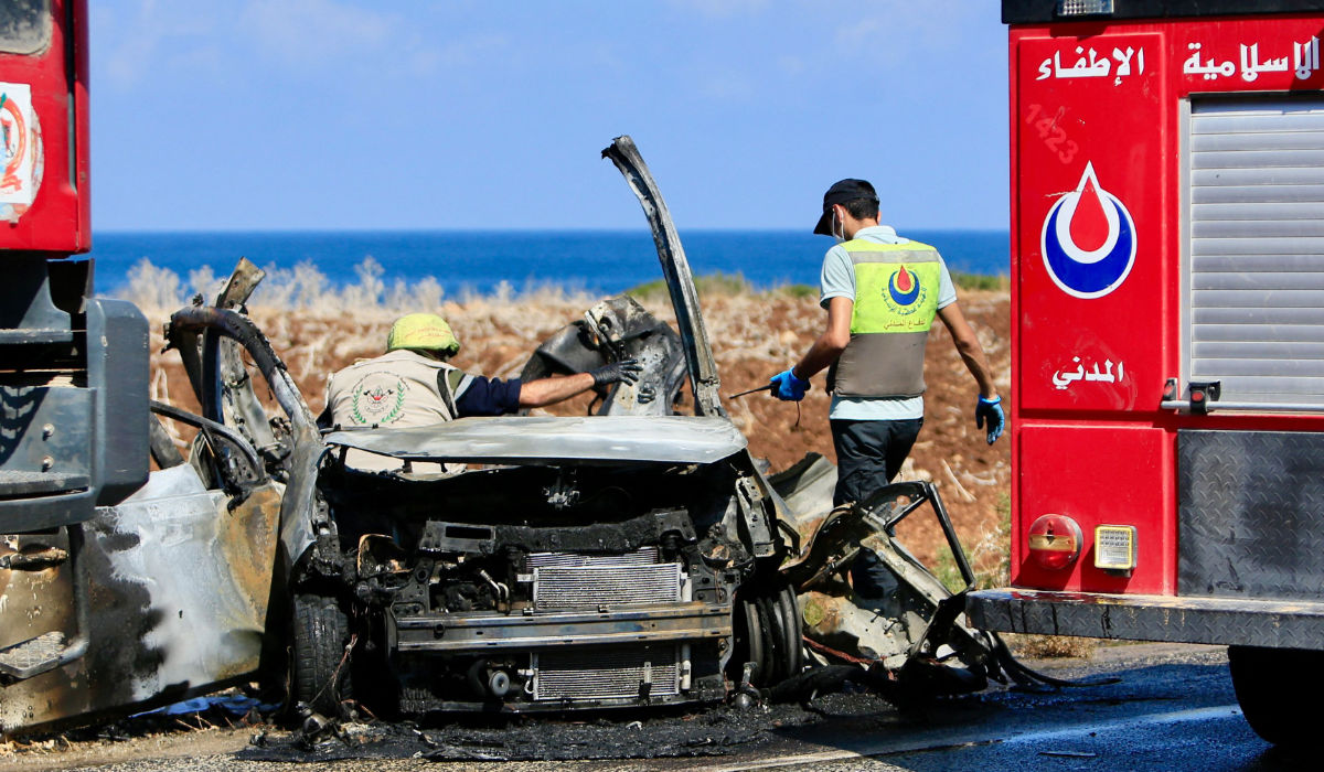Civil Defence teams inspect a charred car that was hit by an Israeli drone strike on the road leading to the southern Lebanese coastal town of Naqoura on the border with Israel on September 2, 2024, as Hezbollah and Israel continued to exchange shelling. (AFP)