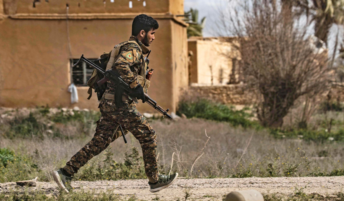 A member of the Syrian Democratic Forces (SDF) runs for cover during shelling on the Daesh group's last holdout of Baghouz, in the eastern Syrian Deir Ezzor province on March 3, 2019. (AFP)