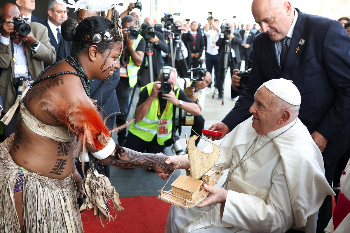 Pope Francis receives a gift from an Indigenous woman on the day of his meeting with the authorities, civil society and the diplomatic corps at APEC Haus in Port Moresby on Sept. 7, 2024. (REUTERS)