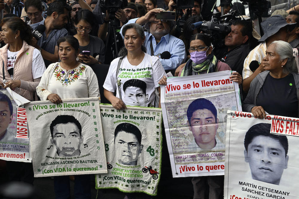 Relatives hold pictures of the 43 missing students from the Ayotzinapa rural teachers’ school in Guerrero as they wait for a meeting with Mexico’s President-elect Claudia Sheinbaum on July 29, 2024. (AFP)