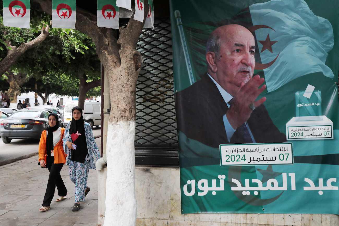 People walk past posters of Algeria’s President Abdelmajid Tebboune outside an election campaign headquarters in Algiers on September 8, 2024. (AFP)