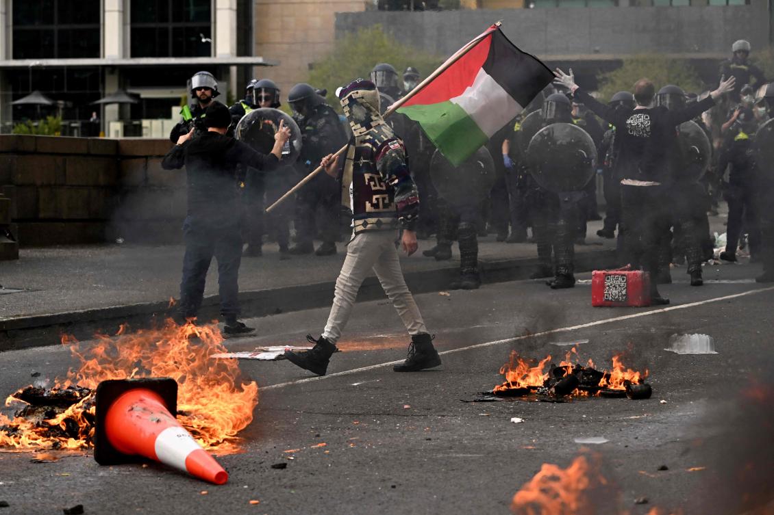 A man waves a Palestinian flag as protesters confront police outside the Land Forces 2024 arms fair in Melbourne on September 11, 2024. (AFP)