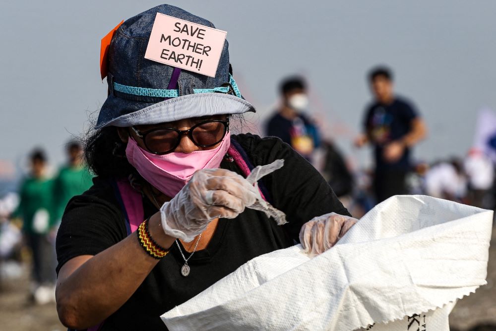 A volunteer picks up trash at Baseco Beach during an event marking the International Coastal Cleanup Day in Manila on Sept. 16, 2023. (AFP)