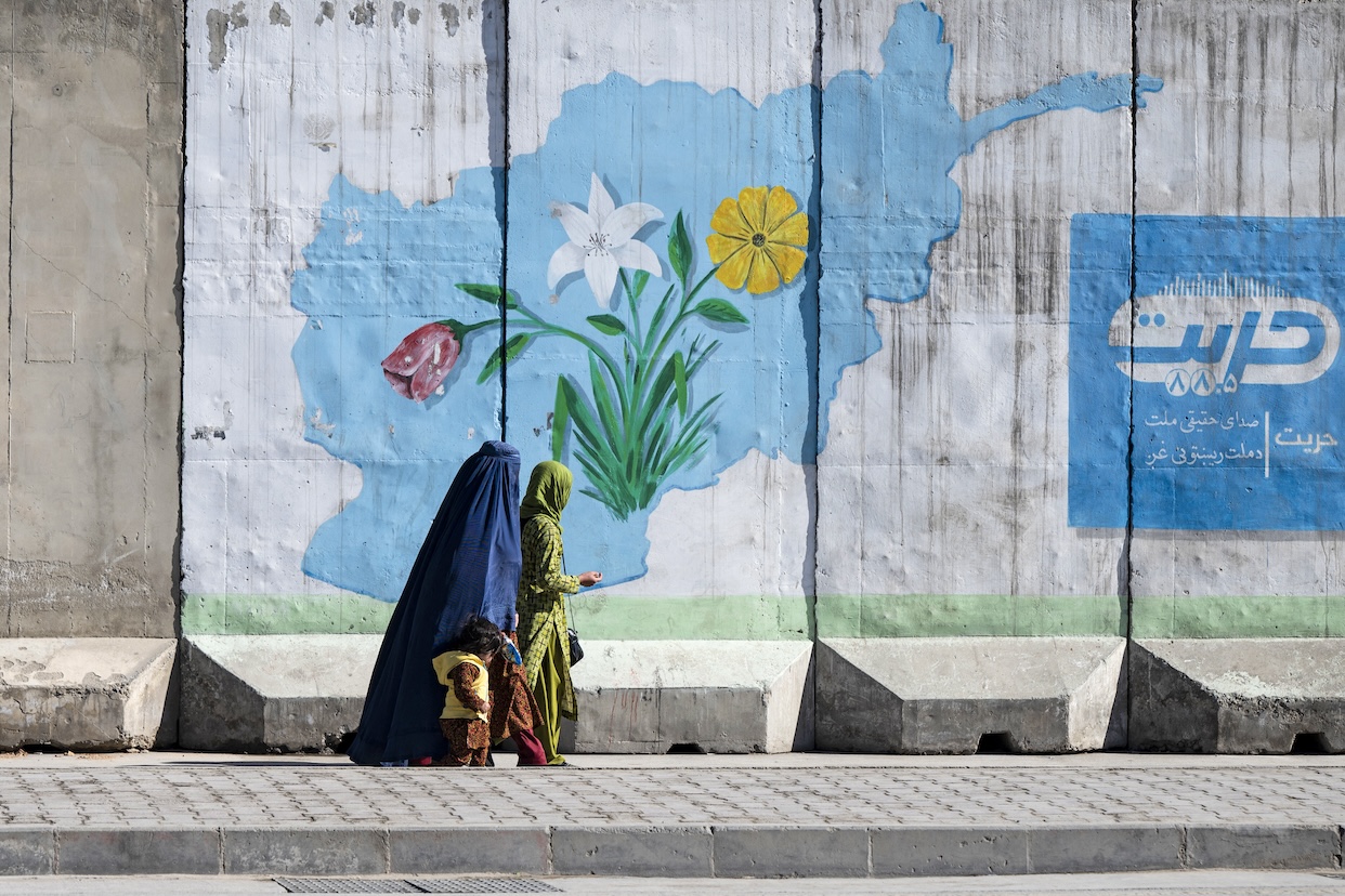 Afghan women walk past a mural with the map of Afghanistan, in Kabul on Feb. 1, 2024. (AFP)