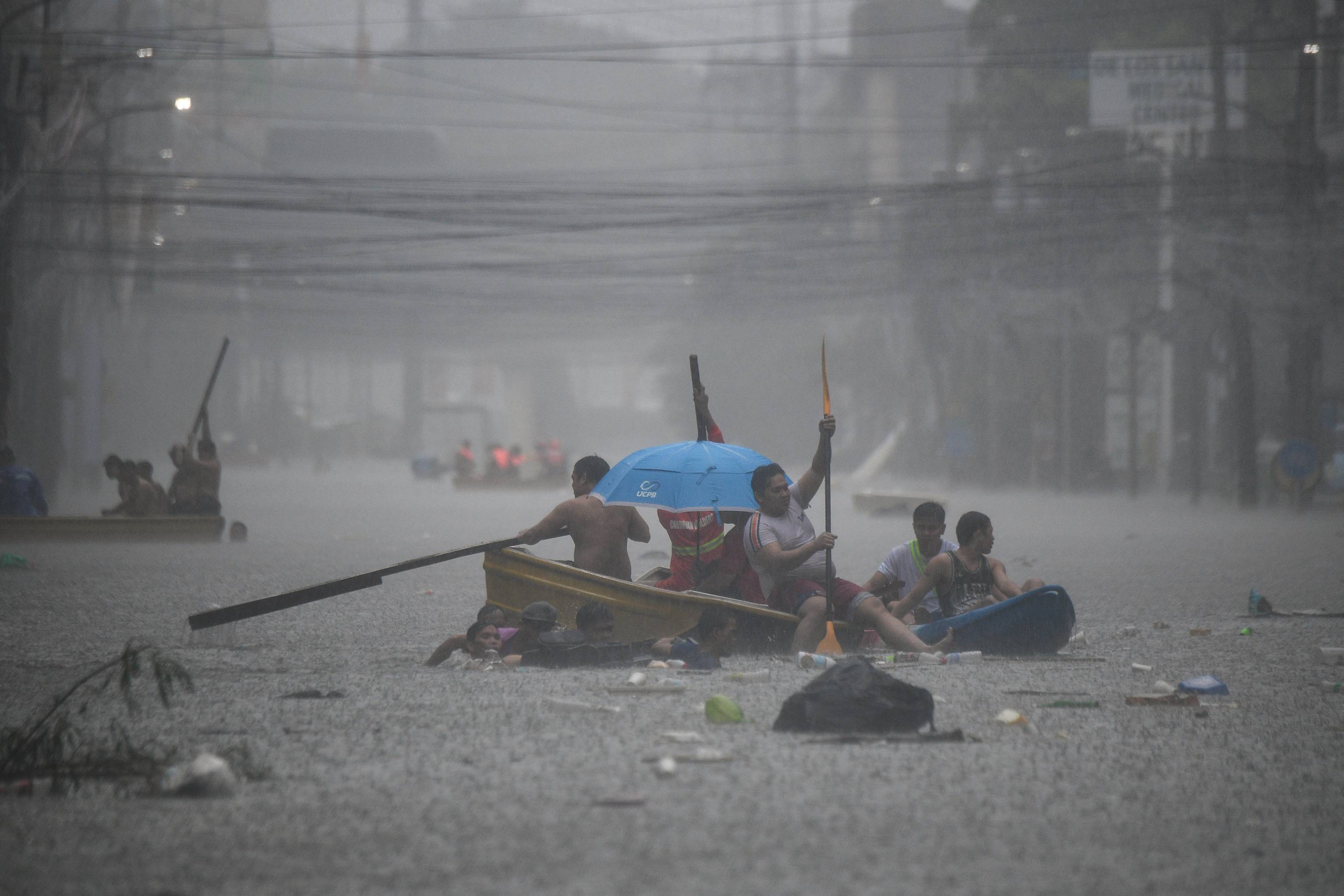 Rescuers paddle their boats along a flooded street in Manila amid heavy rains brought by Typhoon Gaemi. (File/AFP)