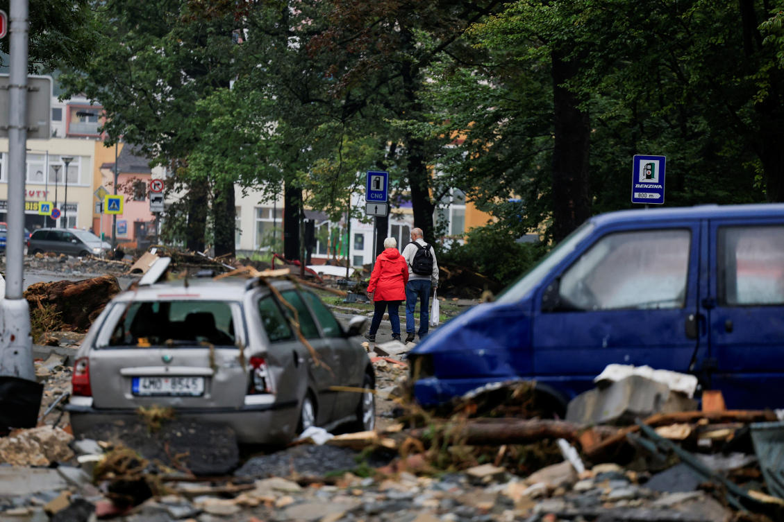 A man and woman walk amidst debris and damaged vehicles on a road, in the aftermath of flooding following heavy rainfalls, in Jesenik, Czech Republic, September 16, 2024. (REUTERS)