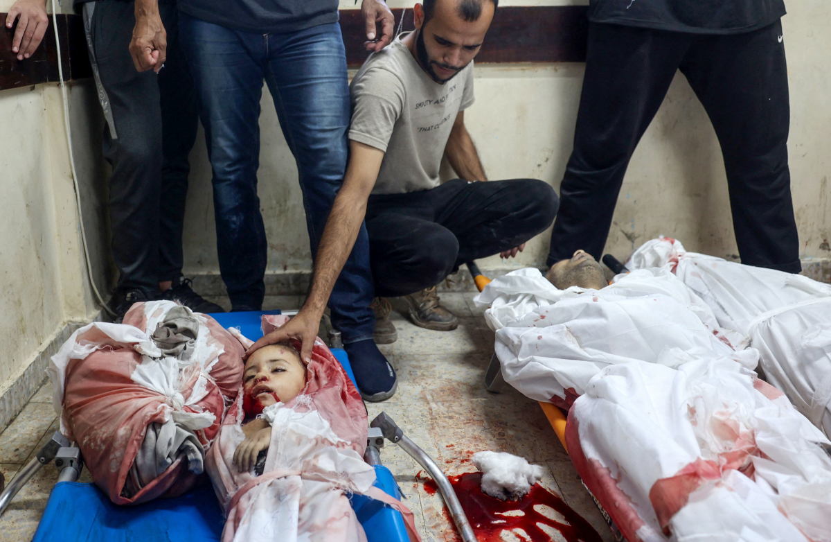 A Palestinian man touches the body of a young victim of Israeli bombardment in Nuseirat in the central Gaza Strip, on September 16, 2024, amid the ongoing war in the Palestinian territory between Israel and Hamas. (AFP)