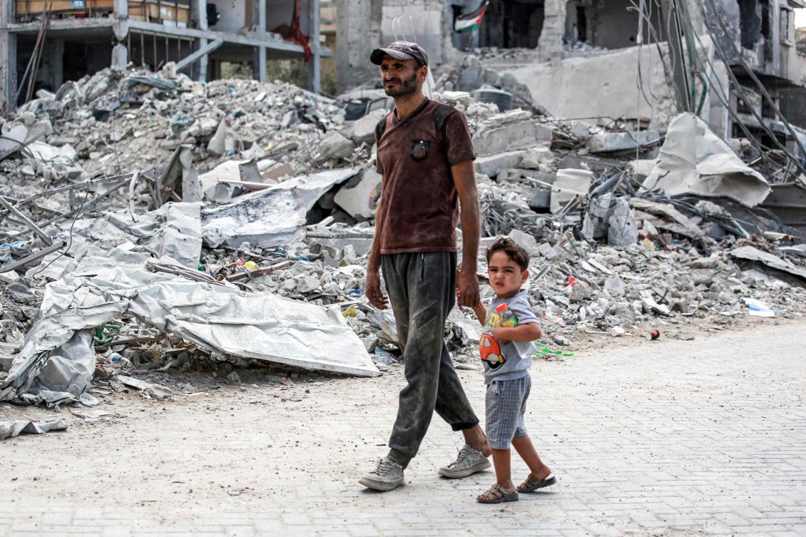 Man and child walk past the rubble of a collapsed building in Khan Yunis in the southern Gaza Strip on September 16, 2024 amid the ongoing war in the Palestinian territory between Israel and Hamas. (File/AFP)