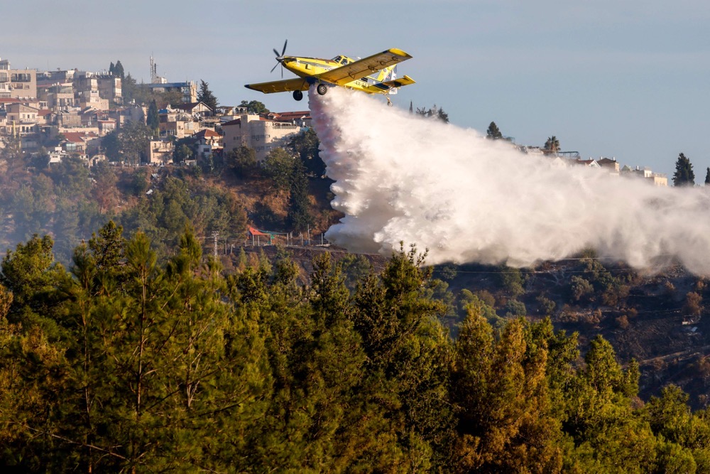 A firefighting aircraft releases flame retardant to extinguish fires caused by rockets launched from southern Lebanon which landed on the outskirts of Safed, in the upper Galilee. (AFP)