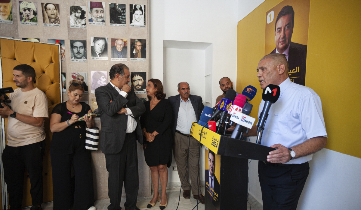 Abdessatar Messaoudi, right, attorney of Tunisian presidential candidate Ayachi Zammel, seen on the poster on the wall, speaks during a press conference after Zammel was sentenced to prison on fraud charges that Messaoudi decried as politically motivated, in Tunis, Monday, Sept. 16, 2024. (AP)