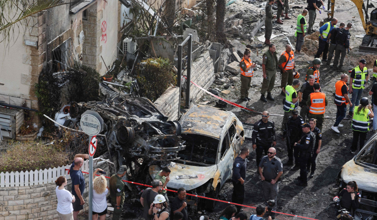 Residents watch as first responders and Israeli security forces gather amid debris and charred vehicles in Kiryat Bialik in the Haifa district of Israel, following a reported strike by Lebanon's Hezbollah on September 22, 2024. (AFP)