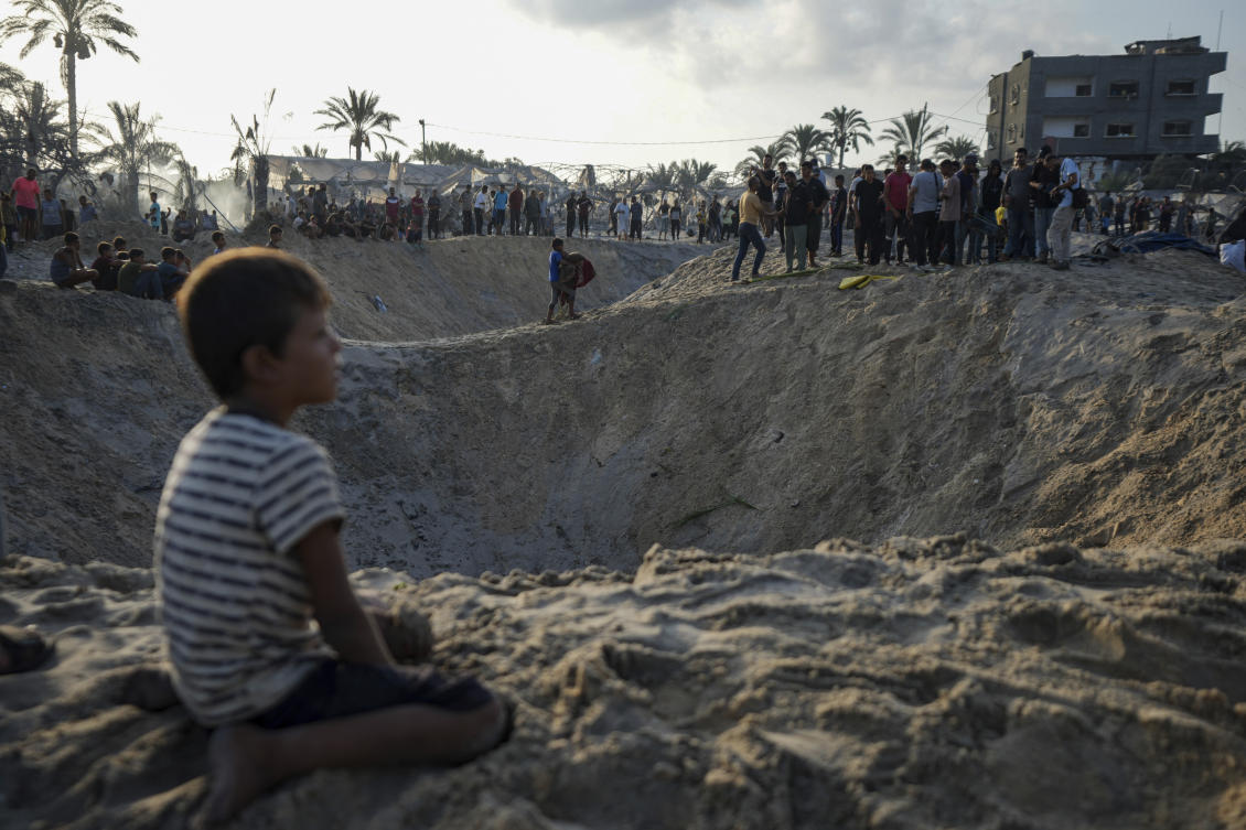 Palestinians look at the destruction after an Israeli airstrike on a crowded tent camp housing Palestinians displaced by the war in Muwasi, Gaza Strip. (File/AP)