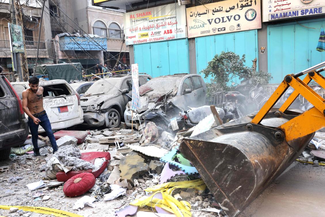 A machine clears debris in a street under a residential building whose top two floors were hit by an Israeli strike in the Ghobeiri area of Beirut’s southern suburbs on September 24, 2024. (AFP)