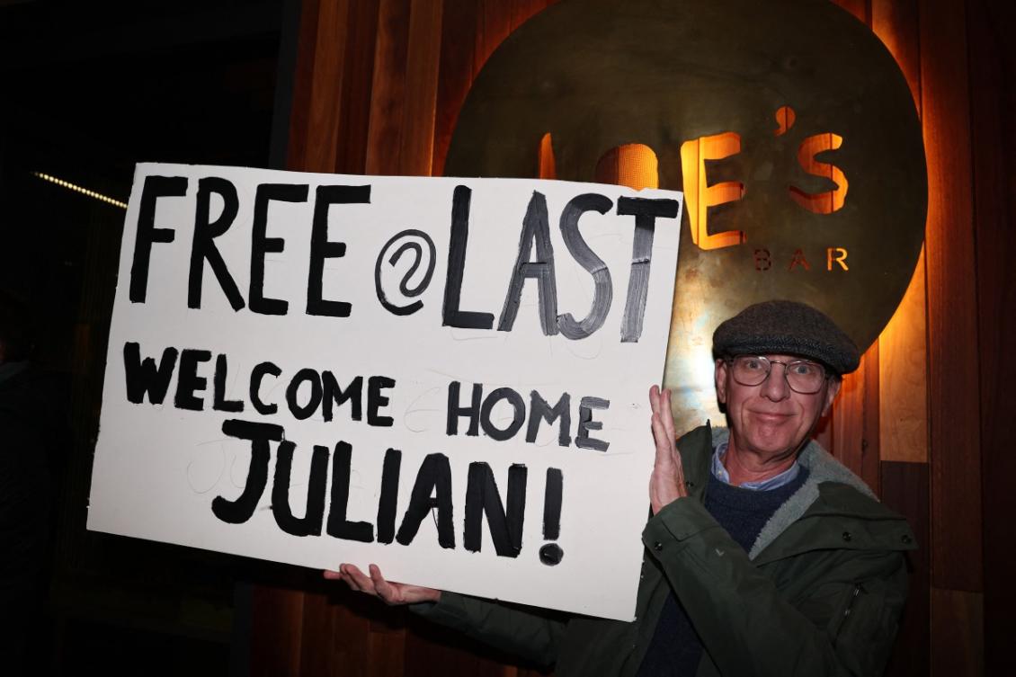 A supporter of WikiLeaks founder Julian Assange holds a welcome sign in Canberra on June 26, 2024, after Assange returned to Australia following a guilty plea at a US court in Saipan to a single count of conspiracy to obtain and disseminate US national defence information. (AFP)