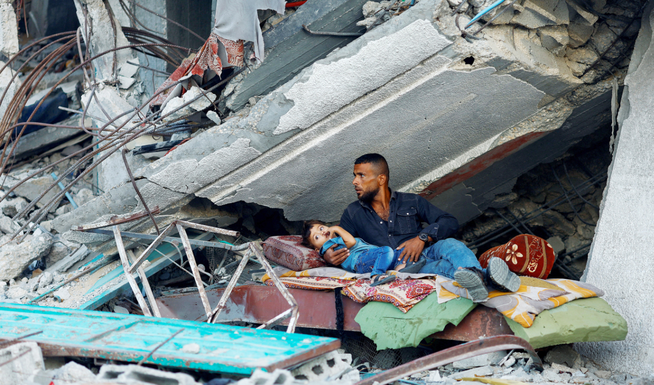 Palestinians rest on Thursday under the rubble of a house destroyed in Israeli strikes in Khan Younis in the southern Gaza Strip. (Reuters)