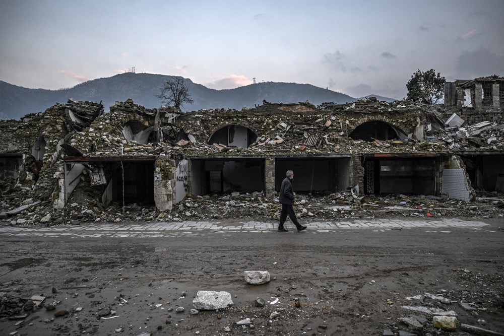 A man walks next to a damaged building in Antakya, Hatay province, on February 5, 2024, after one year the February 2023 earthquake. (AFP)