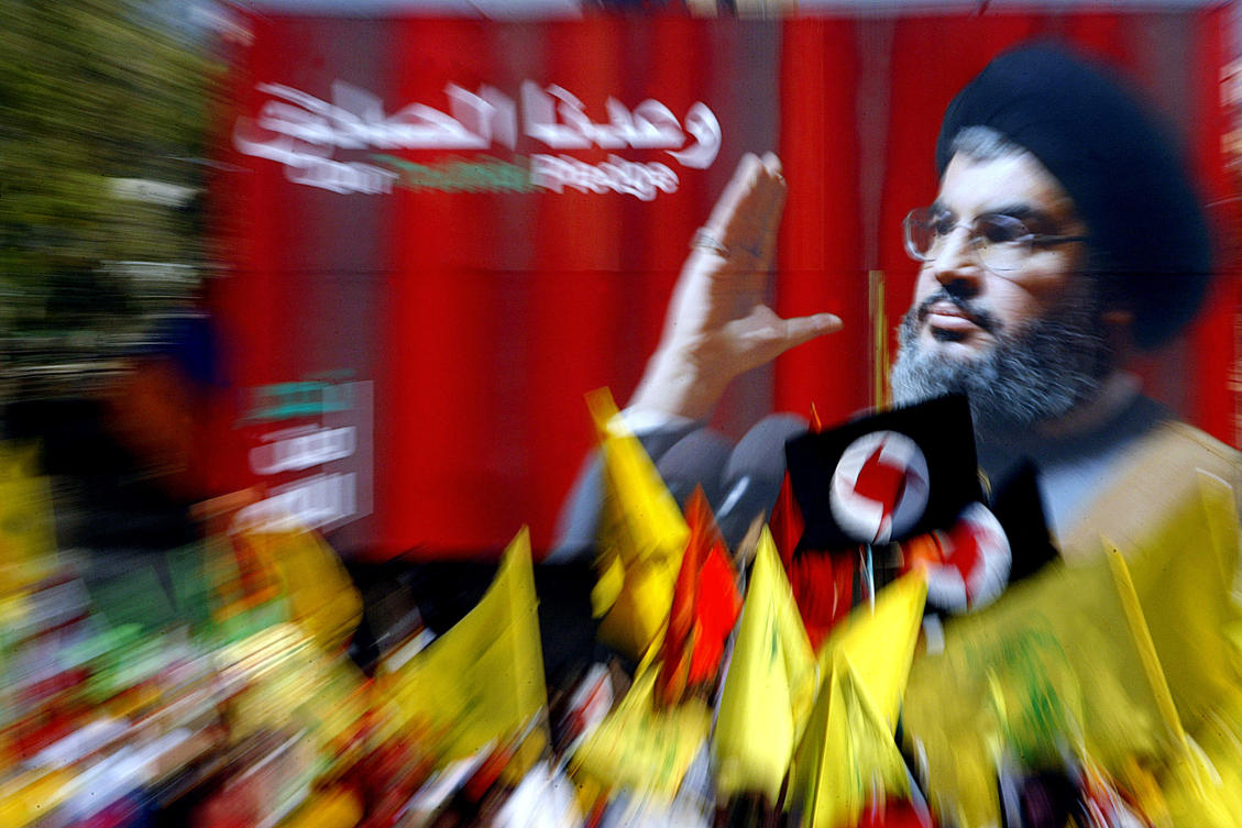 Hezbollah supporters wave flags in front of a giant poster of the group’s chief, Hassan Nasrallah, during a massive rally in the southern suburb of Beirut on Sept. 22, 2006. (AFP)