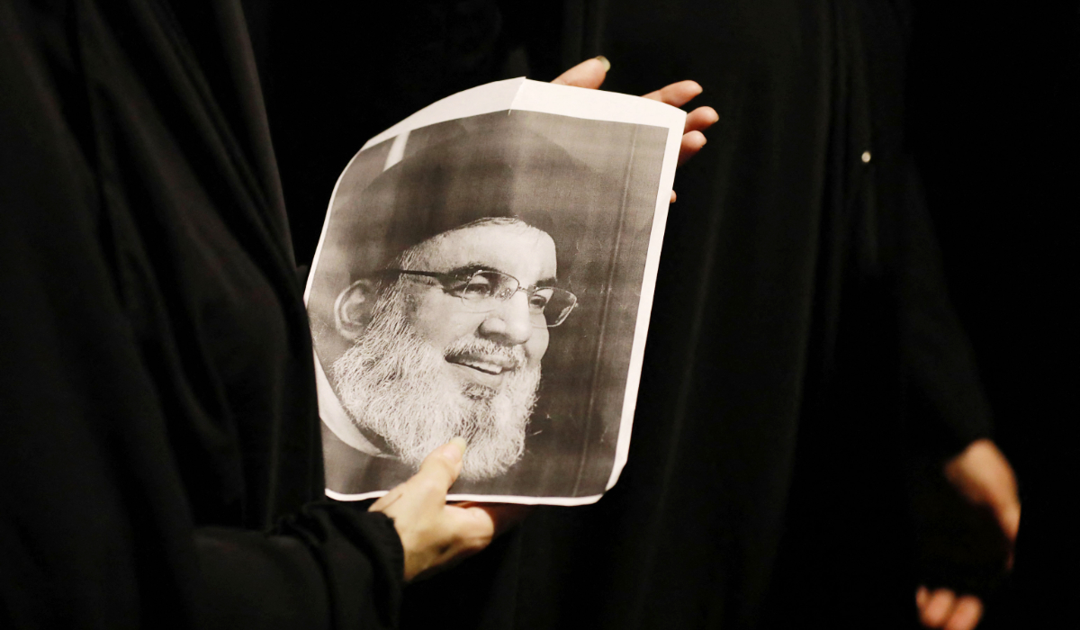 Demonstrators hold pictures of Hassan Nasrallah, late leader of the Lebanese group Hezbollah, during a protest vigil near the suspension bridge leading to Baghdad's Green Zone on September 28, 2024. (AFP)
