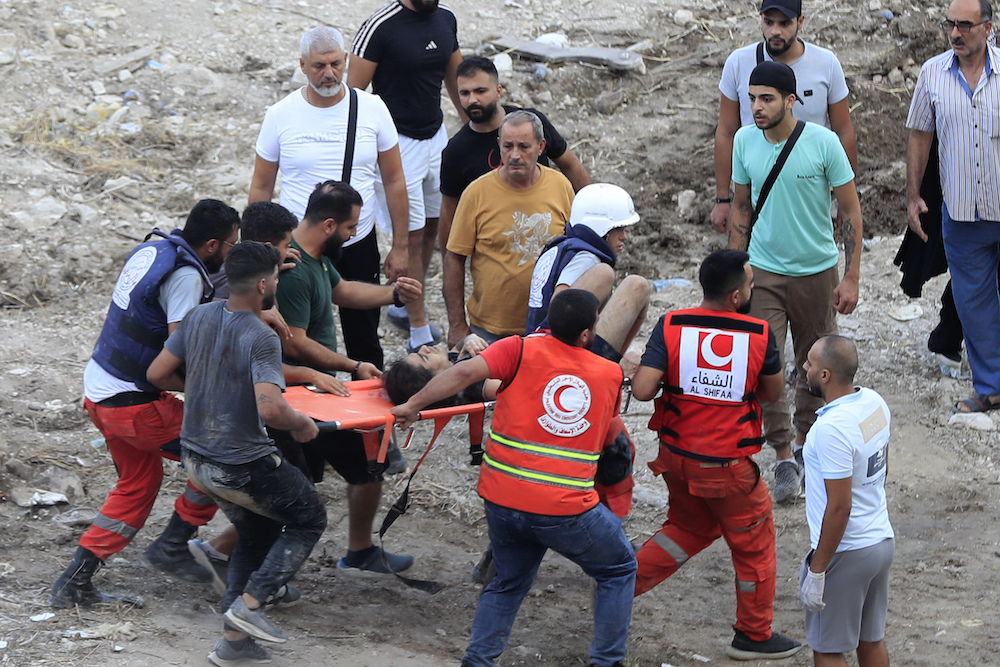 Rescue workers carry a man who was injured after an Israeli airstrike hit two adjacent buildings, in Ain el-Delb neighbourhood east of the southern port city of Sidon, Lebanon. (AP)