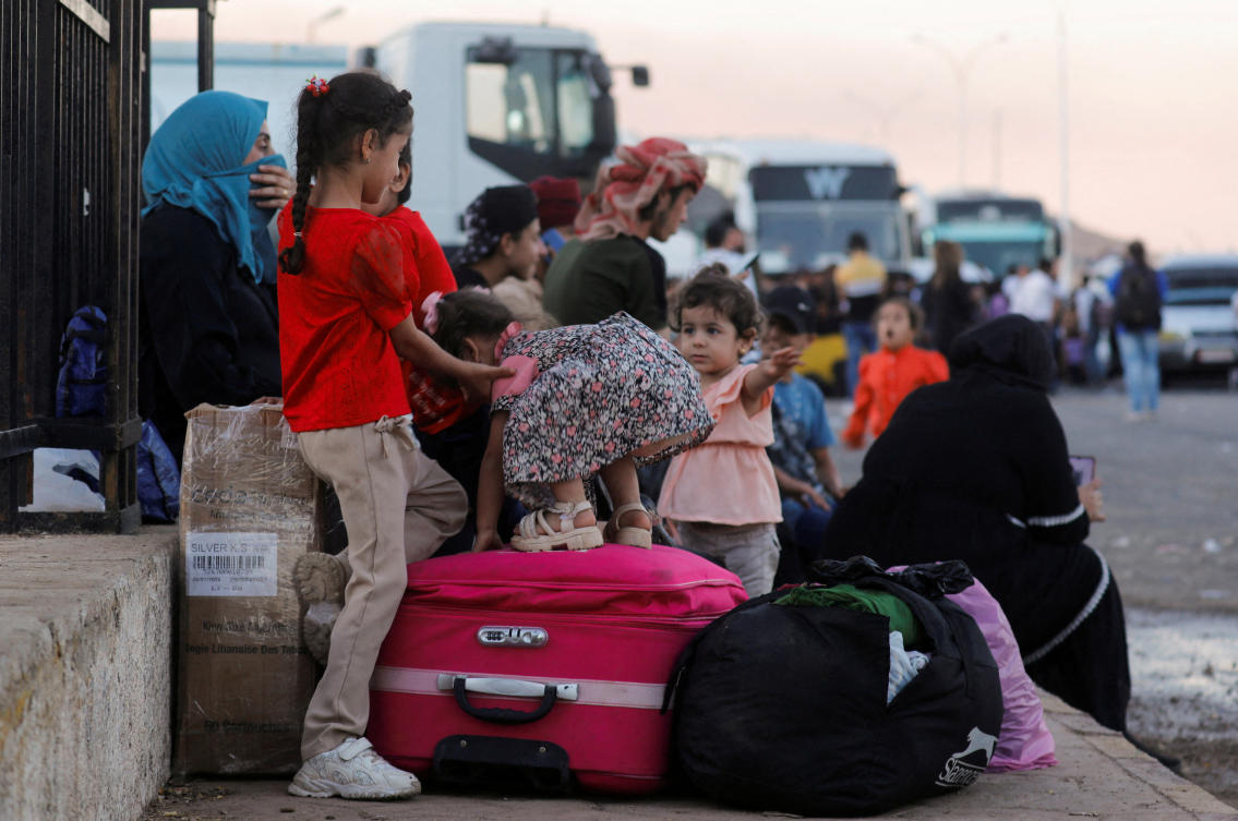 Syrians, who were living in Lebanon and returned to Syria due to ongoing hostilities between Hezbollah and Israeli forces, wait with their belongings at the Syrian-Lebanese border, in Jdaydet Yabous, Syria, September 25, 2024. (Reuters)