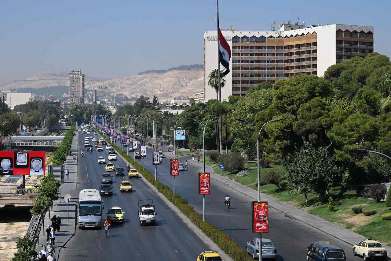 Syrians drive past the Syrian flag at half-mast in the capital Damascus on September 29, 2024, after Syria officially declared a three-day national mourning period following Israel's killing of Lebanon's Hezbollah leader Hassan Nasrallah. (AFP)