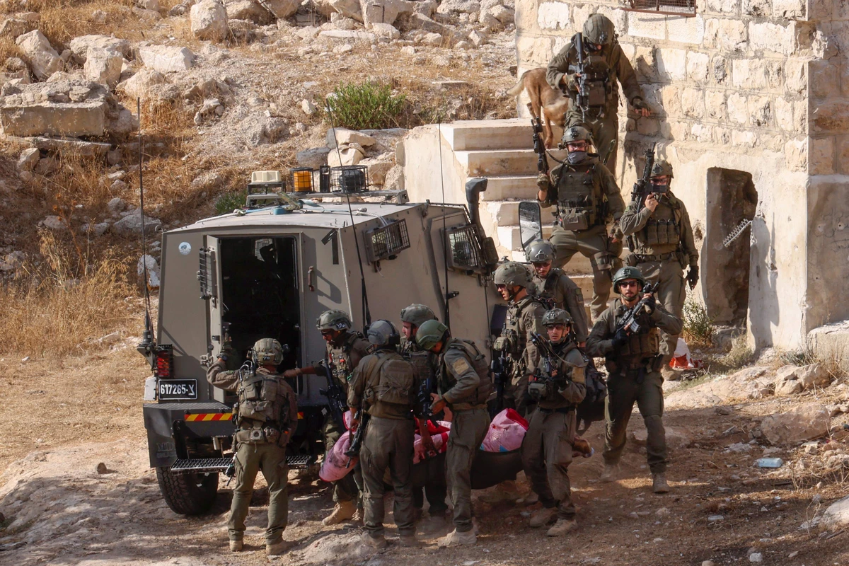 Israeli security forces transport the body of a Palestinian man from an old building during a raid in Hebron city in the occupied West Bank on September 1, 2024. (AFP)