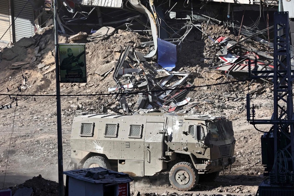 An Israeli armoured vehicle drives along a devastated street in the West Bank. (AFP)