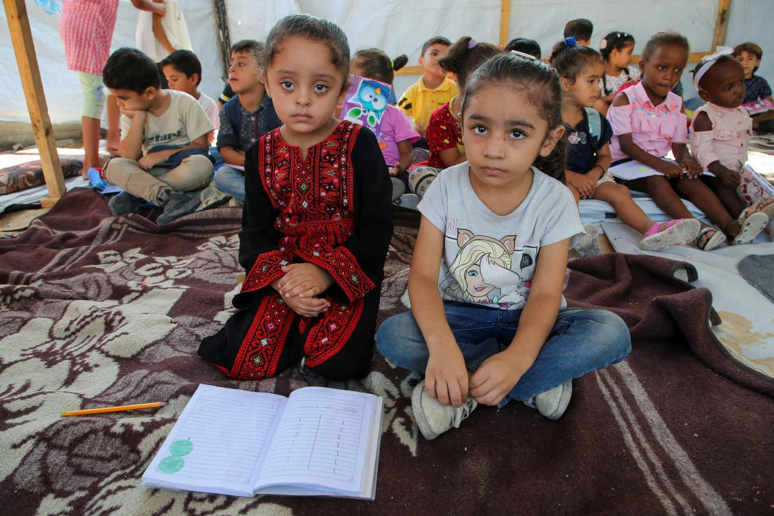 Palestinian students attend a class in a tent set up on the rubble of the house of teacher Israa Abu Mustafa, as war disrupts a new school year, in Khan Younis on Sept. 4, 2024. (Reuters)