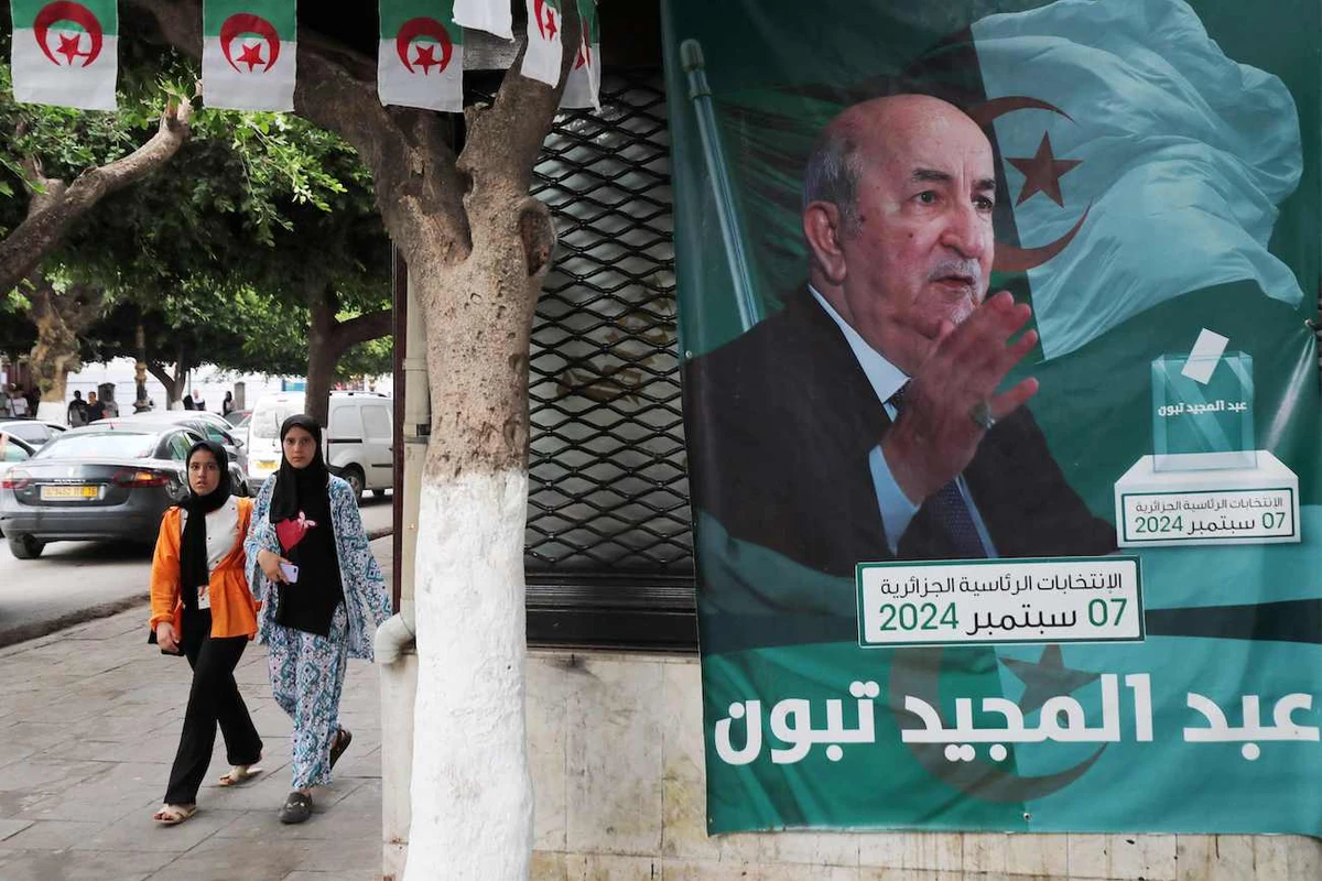 People walk past posters of Algeria’s President Abdelmajid Tebboune outside an election campaign headquarters in Algiers on September 8, 2024. (AFP)