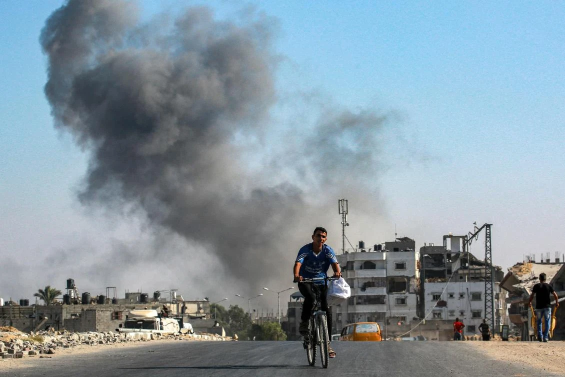 A man cycles as smoke from Israeli bombardment rises behind him in an area that was ordered to be evacuated by the Israeli army in the southeast of Khan Yunis, southern Gaza Strip on Sep. 8. (AFP)