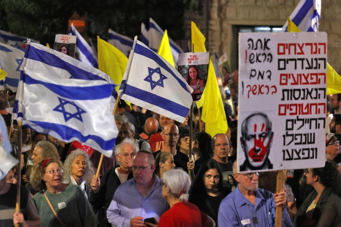 Demonstrators raise placards and Israeli flags during an anti-government protest calling for action to secure the release of Israeli hostages held captive since the Oct. 7 attacks near the residence of the Israeli prime minister in Jerusalem on Sept. 7, 2024. (AFP)