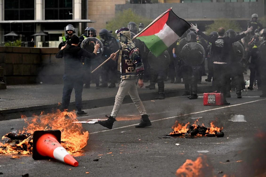 A man waves a Palestinian flag as protesters confront police outside the Land Forces 2024 arms fair in Melbourne on September 11, 2024. (AFP)