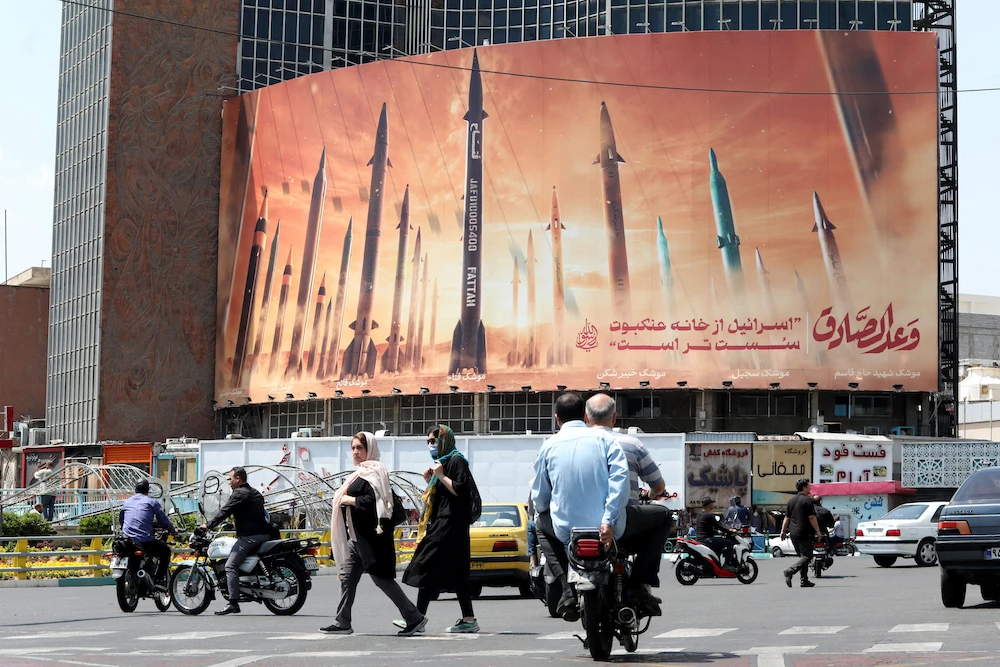 Above, motorists drive their vehicles past a billboard depicting Iranian missiles in Tehran on April 20, 2024. Tehran has condemned additional sanctions for supposed Iran’s recent transfer of missiles to Russia. (AFP file photo)