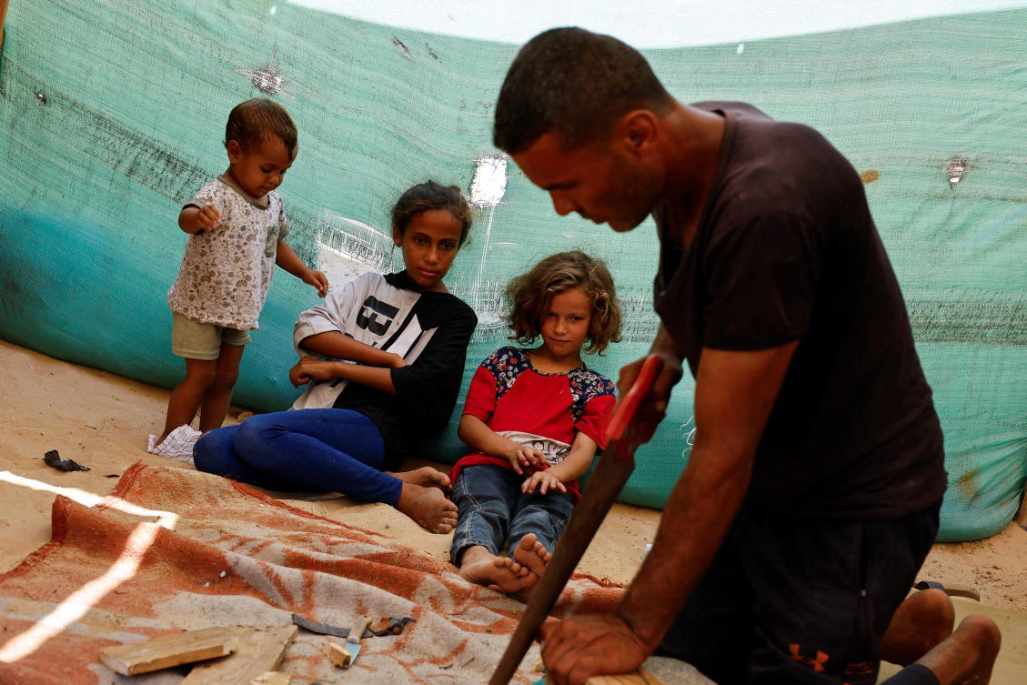 Palestinian Saber Dawas crafts wooden sandals due to a shortage of footwear in the enclave and the lack of financial means to afford those which are available in the market, in Khan Younis on Sept. 9, 2024. (Reuters)