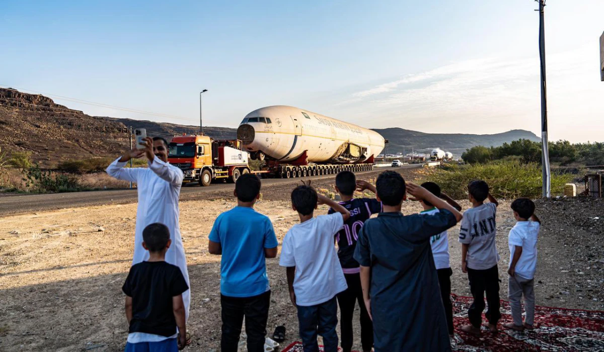 In a memorable viral image, a man takes a selfie next to a group of children giving the retired aircraft a salute on its final journey. (Supplied/X)