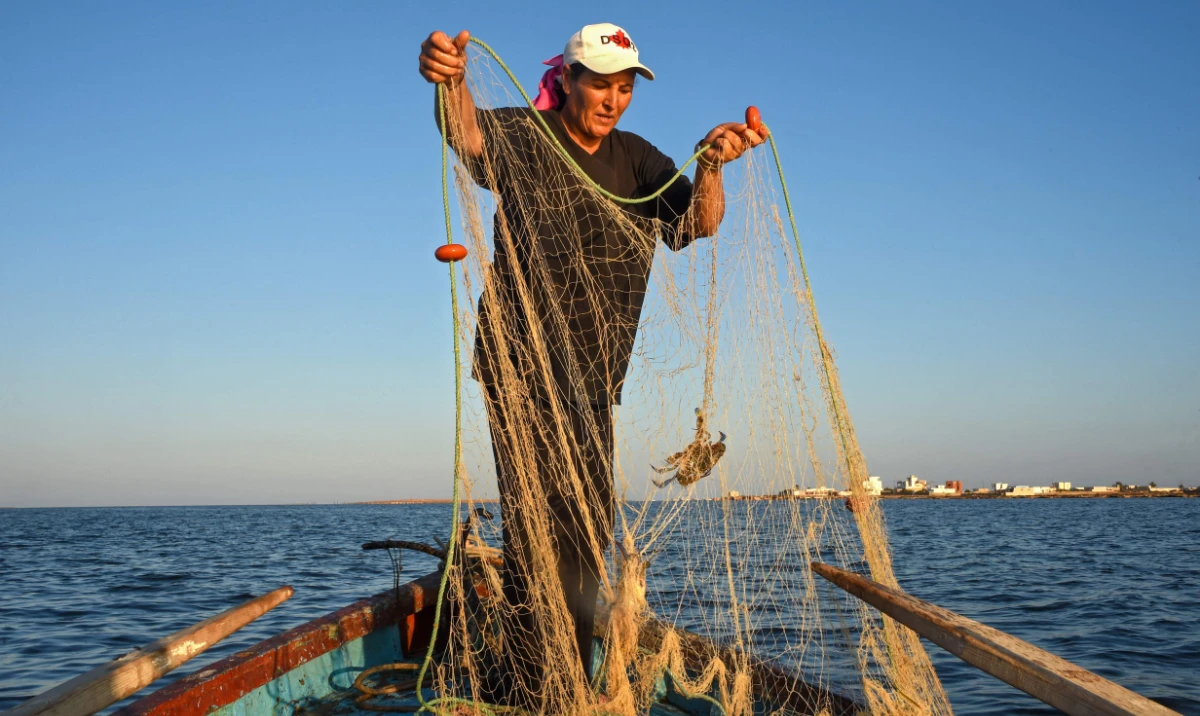 Tunisian fisherwoman Sara Souissi prepares her net in a boat along the coast of Tunisia's Kerkennah Islands in the Mediterranean Sea in the south of the country, on August 8, 2024. (AFP)