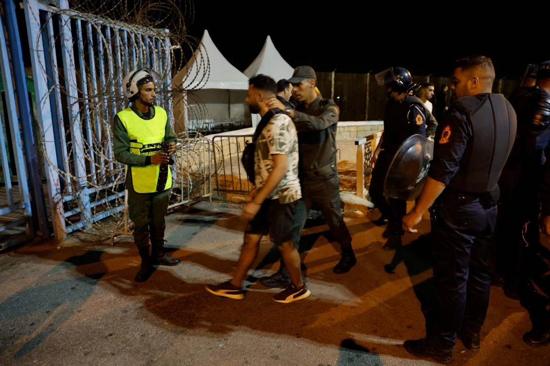 Members of Morocco’s Auxiliary Forces arrest a man as they deploy to prevent illegal crossings of the land border fence with Spain’s African enclave of Ceuta near Fnideq in northern Morocco on Sept. 15, 2024. (AFP)